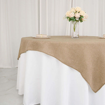 Brown burlap tablecloth draped over a white table with flowers.