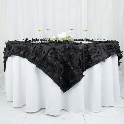 Black tablecloth with leaf design draped over a white table.