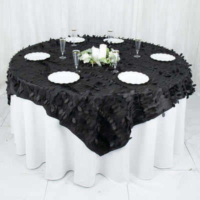 Black tablecloth with leaf design on round table set for dining.