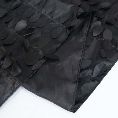 Black fabric with leaf-shaped appliqués on a smooth surface.