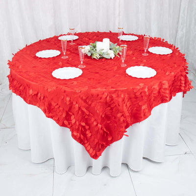 Red tablecloth with leaf design on a round table, set for dinner.