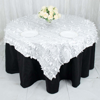 White floral tablecloth on a round table with black skirt and floral centerpiece.