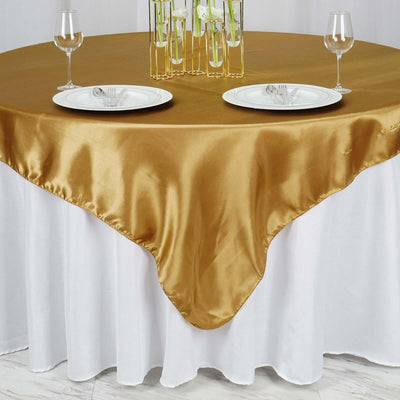 Gold satin tablecloth draping over a white table with plates and glasses.