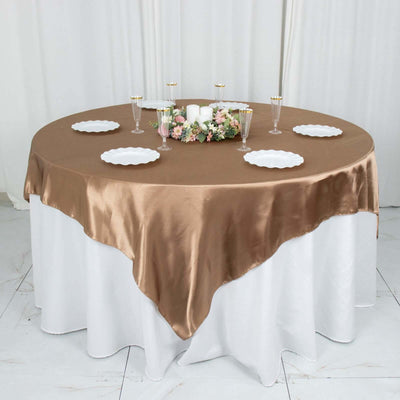 Elegant round table set with a brown satin tablecloth and floral centerpiece.