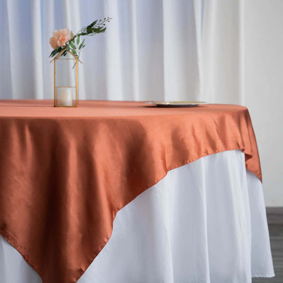 Orange satin tablecloth draped elegantly over a white table.
