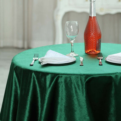 Elegant green table setting with wine bottle, glass, and cutlery.
