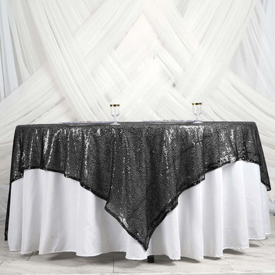 Sequin tablecloth with a black and silver design on a white table.