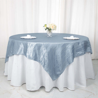 Elegant blue tablecloth draped over round table with floral centerpiece.
