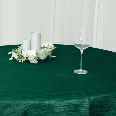 Elegant green tablecloth with candles and a glass on a dining table.