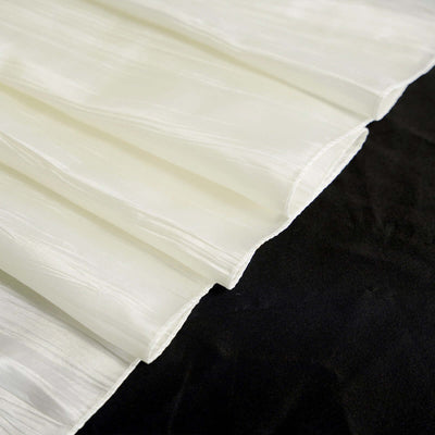 Pleated white fabric draping on a dark surface.