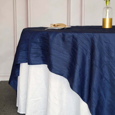 Elegant navy and white tablecloth draped over a table with decorative plate.