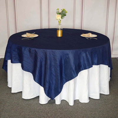 Navy blue round tablecloth draped elegantly on a table with a floral centerpiece.