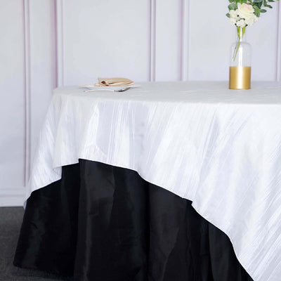 Elegant white and black tablecloth draping over a table with a floral centerpiece.