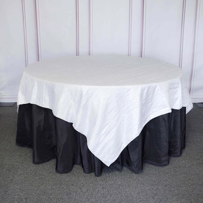 Round table covered with a white and black tablecloth.