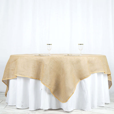 Burlap table overlay with golden trim on a white tablecloth
