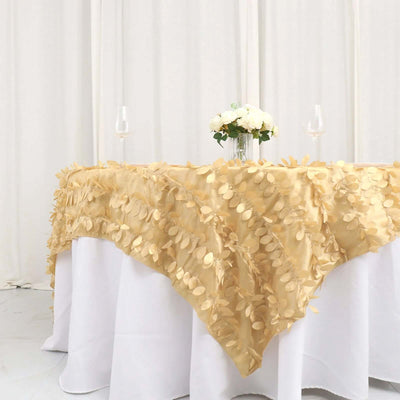Gold leaf tablecloth draped elegantly over a white table with floral centerpiece.