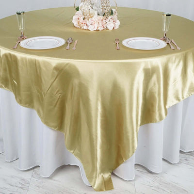 Gold satin tablecloth draped elegantly over a round table setting.
