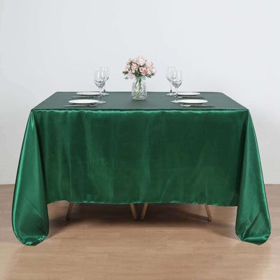Green satin tablecloth draped over a table set for dining.