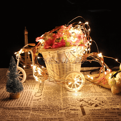 Decorative flower basket with fairy lights, set against a dark background.