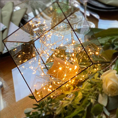 Decorative mirror with fairy lights, styled with greenery and floral accents.