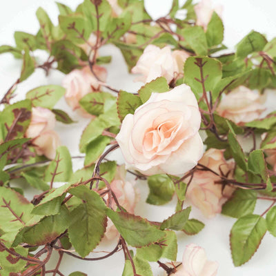 Artificial pink rose garland with green leaves on a white background