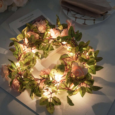 Floral wreath with soft lights and greenery on a table.