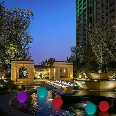 Colorful floating orbs in a serene evening garden setting with a fountain.