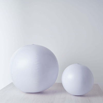 White inflatable balls of varying sizes on a plain backdrop