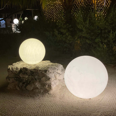 Glowing decorative spheres on a stone base in an outdoor setting.
