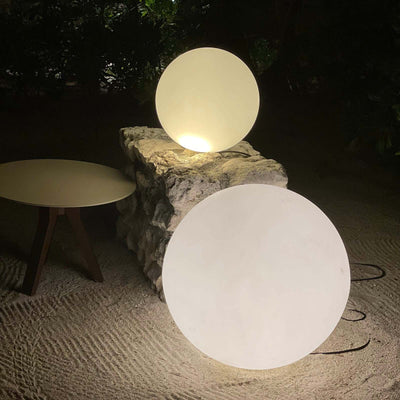 Modern round illuminated lamps on a stone surface at night.