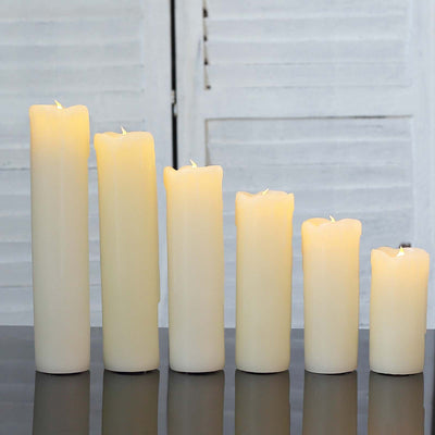 Assorted ivory candles in varying heights on a reflective surface.