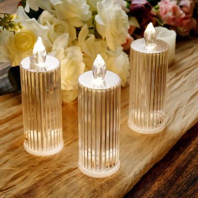 Three elegant LED candles with a ribbed design, glowing softly against a floral backdrop.