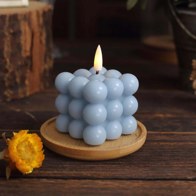Blue bubble candle on a wooden plate with a lit flame.
