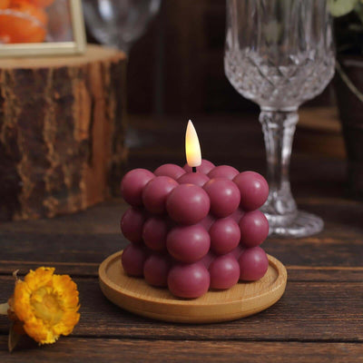 Purple bubble candle on a wooden tray with a flower beside it.