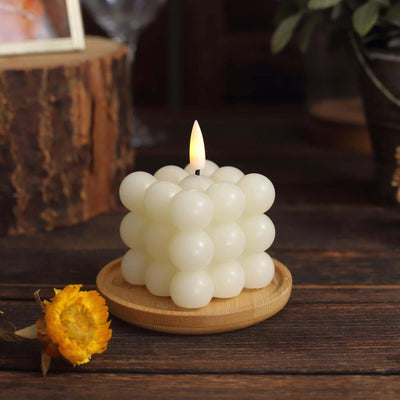 Decorative bubble candle on a wooden plate, lit with a warm flame.