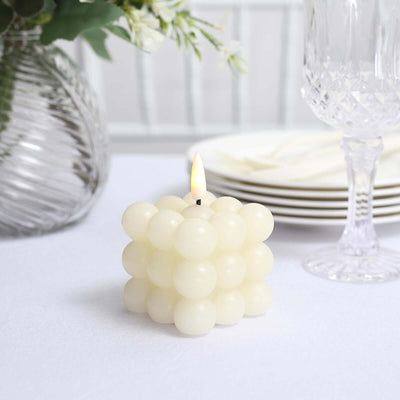 White bubble candle with a lit wick on a table setting.