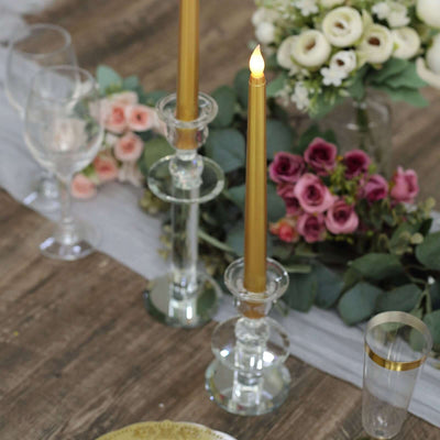 Elegant gold candlesticks with vibrant floral arrangements on a rustic table setting.