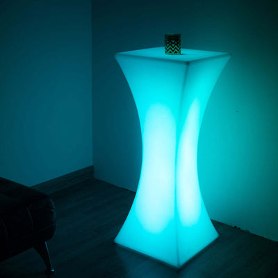 Modern glowing side table in teal with a decorative candle on top.