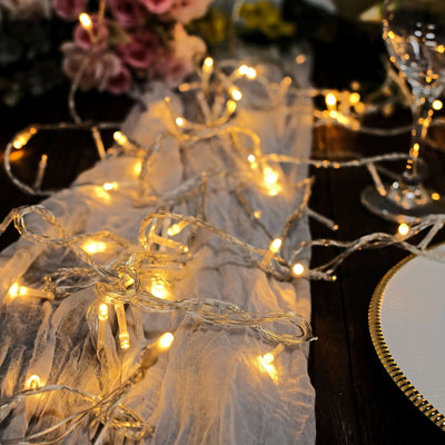 Warm white fairy lights on a table with floral decor and glassware.