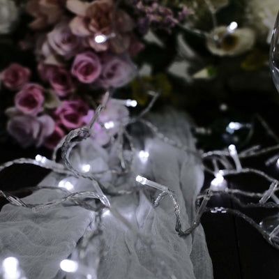 String lights on a soft fabric with flowers in the background.