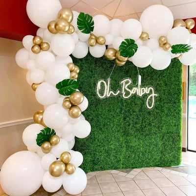 Balloon arch with greenery and "Oh Baby" neon sign for a baby shower.