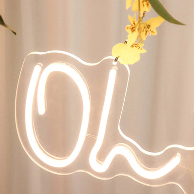 Neon "OL" sign with floral accents hanging in a soft light setting.