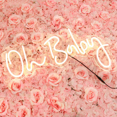 Neon sign "Oh Baby" against a pink rose petal backdrop.