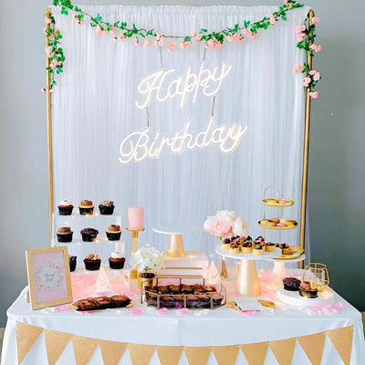 Birthday party dessert table with cupcakes, pastries, and decorative elements.