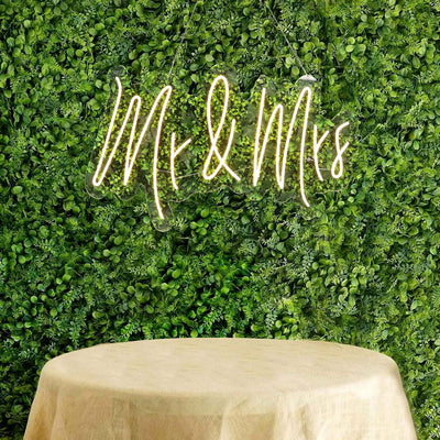 "Mr & Mrs neon sign displayed against a lush green backdrop."