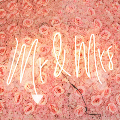 "Neon 'Mr & Mrs' sign against a pink floral backdrop."