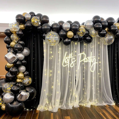 Party balloon arch with fairy lights and "Let's Party" neon sign.