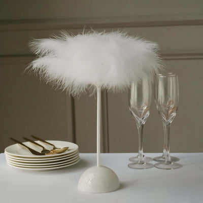 White feather lamp on a white base with elegant tableware in the background.