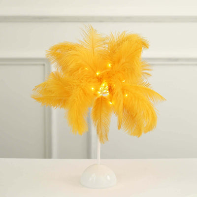 Yellow feather decorative tree with lights on a white base.