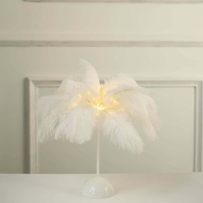White feather lamp with warm LED lights on a simple base.